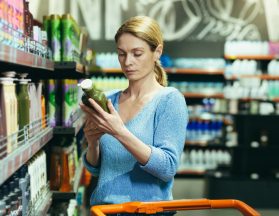 Female chooses and examines product on the supermarket shelves.