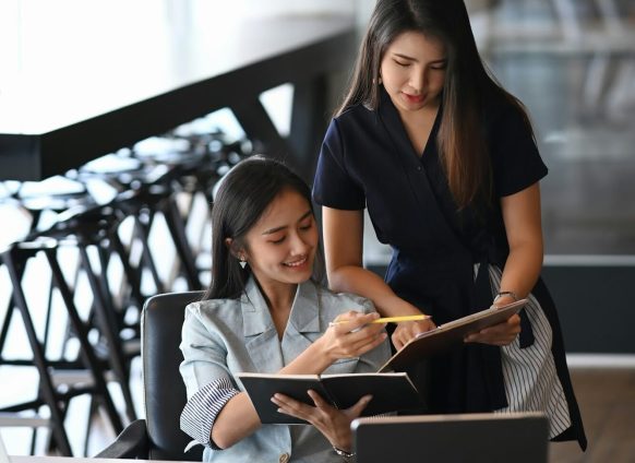 Two young businesswoman using digital tablet and discussing business plan.